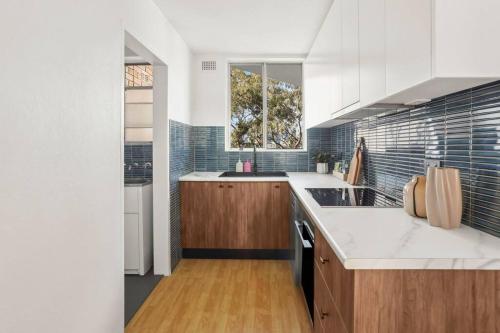 une grande cuisine avec des comptoirs blancs et une fenêtre dans l'établissement Glebe Tranquil Retreat - 2bd with parking, à Sydney