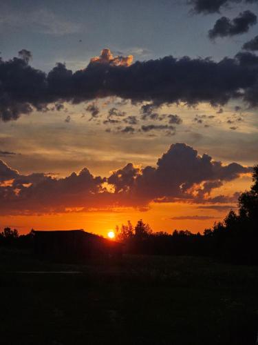 a sunset with the sun setting in the sky at Lāsītes in Lielvārde