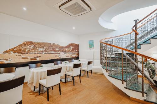 a restaurant with tables and chairs and a staircase at Bi Hotel in Porto Ercole
