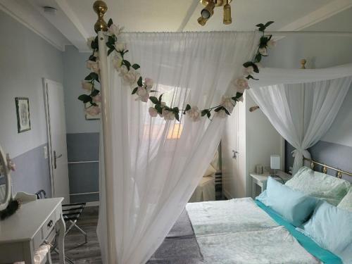 um quarto com uma cama com cortinas brancas e flores em Ferienwohnung Leon em Langelsheim