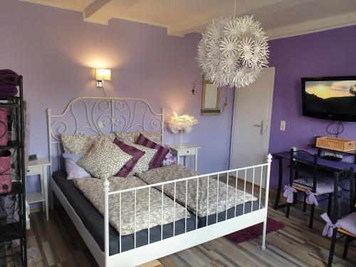 um quarto com uma cama branca e paredes roxas em Ferienwohnung Leon em Langelsheim