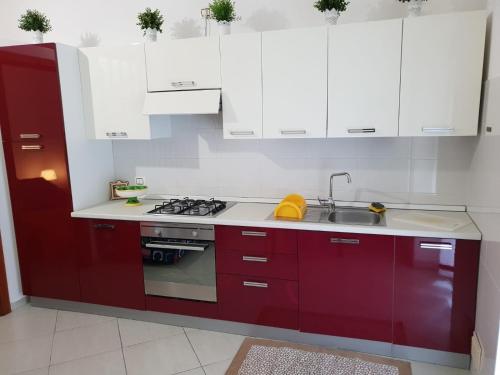 een keuken met rode en witte kasten en een wastafel bij Nonna Rosa in Margherita di Savoia