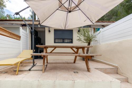 a picnic table and a chair and an umbrella at Gîte rénové Calanque La Vesse in Le Rove
