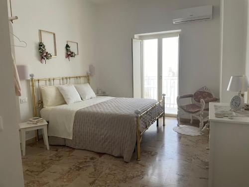 a white bedroom with a bed and a window at ELDOH’ in Bernalda