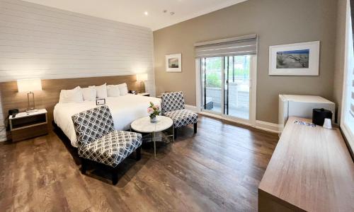 a hotel room with a bed and two chairs and a table at Colonial Hotel & Suites in Grand Bend