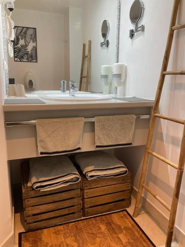 a bathroom with a sink and a counter with a towel shelf at Chambres d’hôtes de l’Ancienne Auberge in Thaon