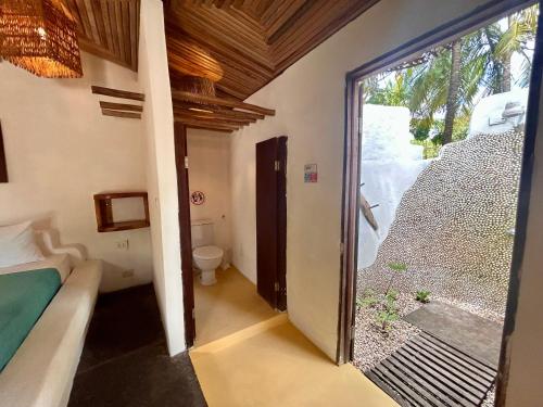a room with a bed and a bathroom with a window at Pousada Maresia in Atins