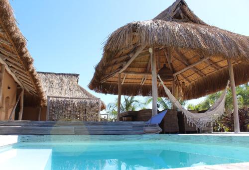 a swimming pool with a straw umbrella and a hammock at Sunset Villa - Beachfront Villa with Private Pool by Karula in Cabo Nhamua
