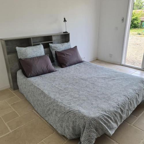 une chambre avec un grand lit avec des oreillers dessus dans l'établissement Les glycines-piscine à débordement, à Rians