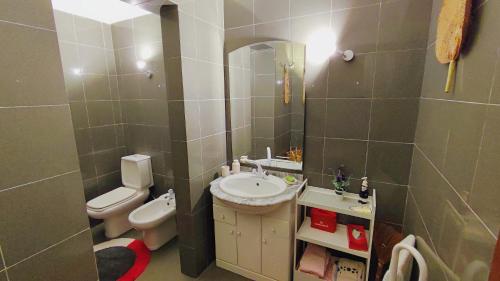 a bathroom with a sink and a toilet and a mirror at LunaSol in Costa da Caparica