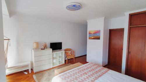 a bedroom with a bed and a dresser with a television at LunaSol in Costa da Caparica