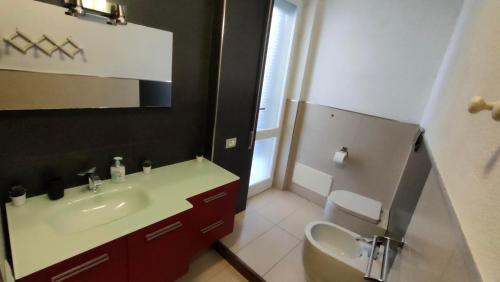 Un baño con lavabo, inodoro y espejo. en La Tua Sosta, en Quartu SantʼElena