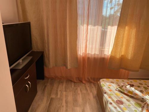 a room with a bed and a television and curtains at Casa Stoian in Costinesti