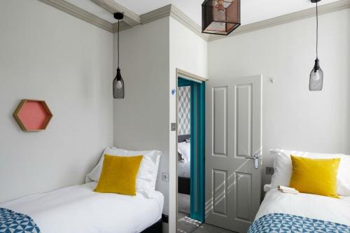バースにあるDream Stays Bath - Beau Streetのドア付きの部屋に黄色い枕が付いたベッド2台が備わります。
