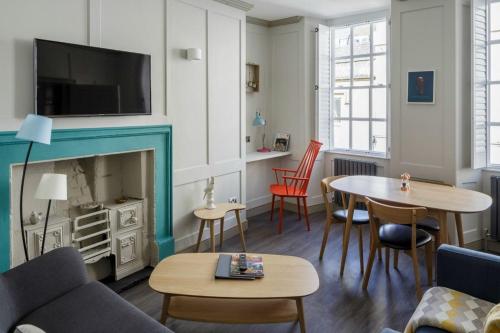 a living room with a fireplace and a table and chairs at Dream Stays Bath - Beau Street in Bath