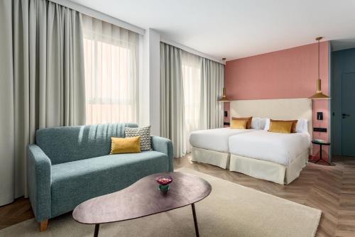 Habitación de hotel con cama, sofá y silla en Aparthotel Tribunal en Madrid