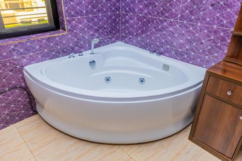 baño púrpura con bañera blanca. en Kigali Wings Apartment 7 A en Kigali