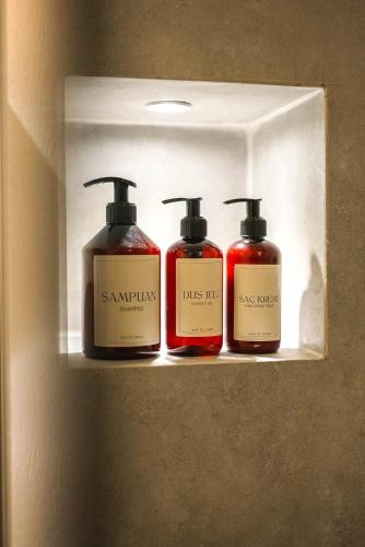 three bottles of soap sitting on a shelf at Hotel Club-E in Fethiye