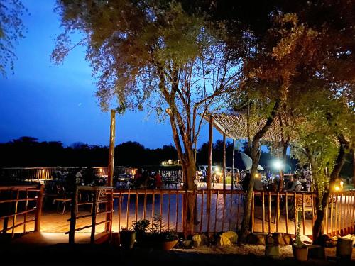 a patio with a fence and trees at night at Crocodile Pools Resort in Gaborone