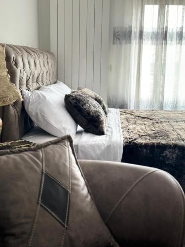 a bed with two pillows and a couch in a room at City Center Cacak in Čačak