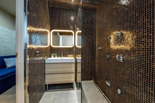 y baño con lavabo y ducha con azulejos marrones. en Il Giardino di Agata en Mascalucia