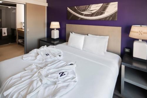 a hotel room with a bed with white sheets at Hyatt House Chicago/Evanston in Evanston