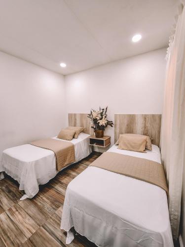 two beds in a room with white walls and wooden floors at Hotel Radoa in El Banco