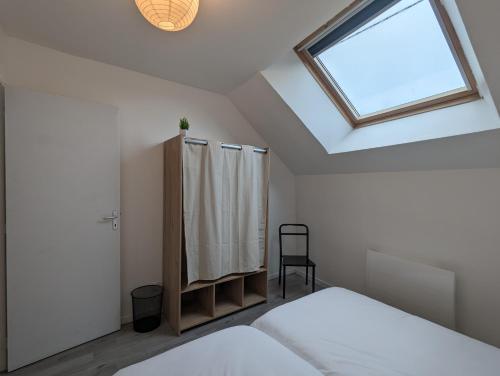 Schlafzimmer mit einem Dachfenster, einem Bett und einem Fenster in der Unterkunft Grande maison avec extérieur, jacuzzi et billard in Vierzon