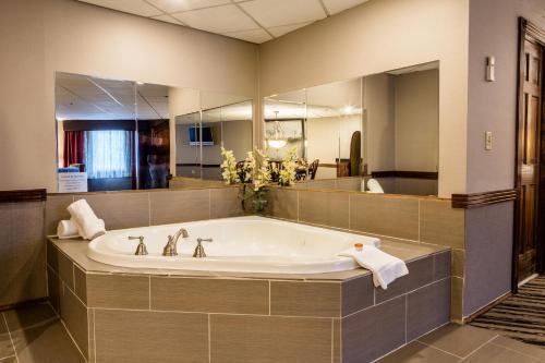 a large bathroom with a tub and a large mirror at Colonial Hotel in Gardner