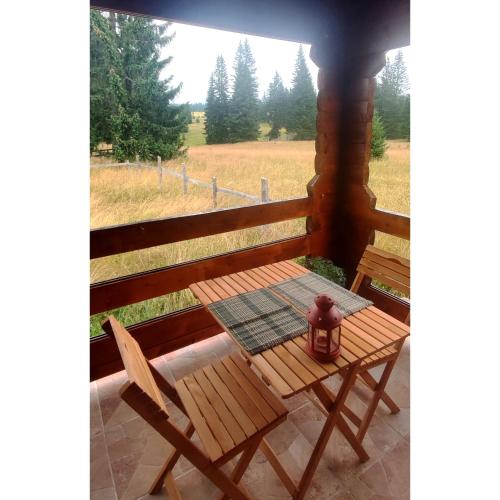 a table and chairs on a porch with a view of a field at Estia in Žabljak