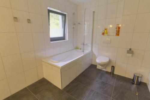 a white bathroom with a tub and a toilet at Haus Johendre in Rennweg