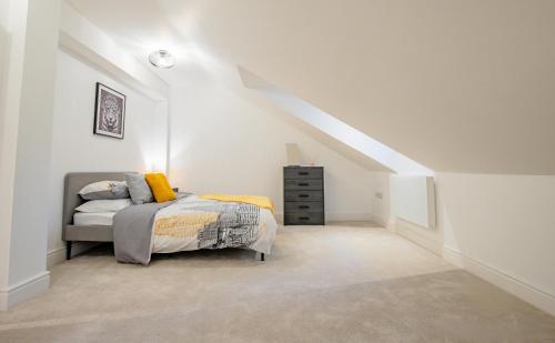 a white bedroom with a bed and a dresser at Guest Homes - Sedlescombe Apartment in Rugby
