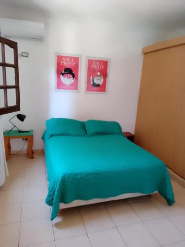 a bedroom with a green bed with two pictures on the wall at Departamento con terraza in Corrientes