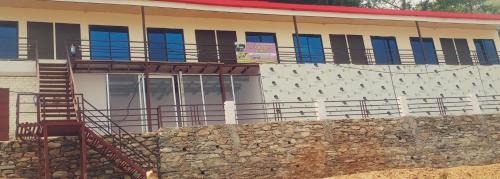 a building with a staircase in front of a stone wall at Dev bhoomi resort in Gupta Kāshi