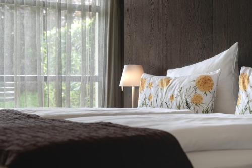 - une chambre avec un lit doté d'oreillers et d'une fenêtre dans l'établissement Golfhotel Gut Neuenhof, à Fröndenberg/Ruhr