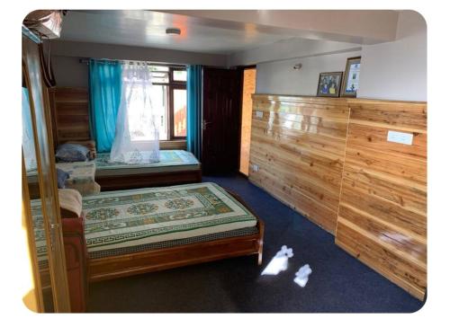 ダージリンにあるTashiling Homestayのベッドが2つと窓がある小さな部屋