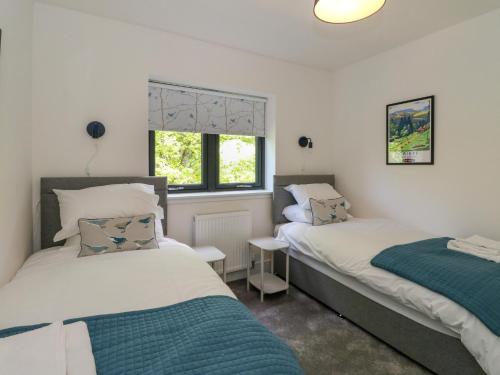 a bedroom with two beds and a window at Oakbank Mews in Aberfeldy