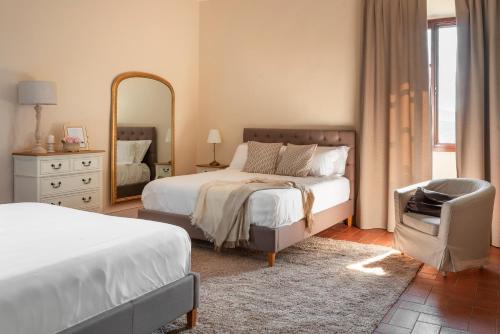 - une chambre avec 2 lits, un miroir et une chaise dans l'établissement Villa Erbaia Relais de Charme, à Barberino di Mugello