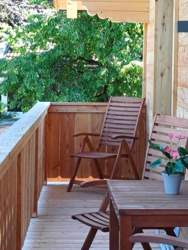 a wooden deck with two chairs and a table at Apartments Haufhof , Haus im Ennstal bei Schladming in Haus im Ennstal