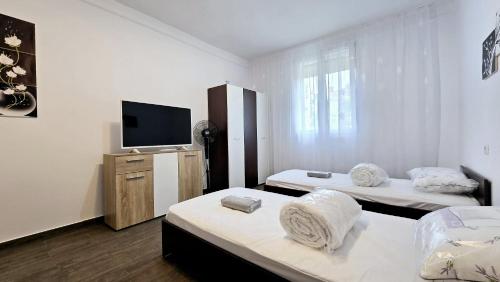 a room with two beds and a flat screen tv at Apartament 3 camere Hd in Hunedoara