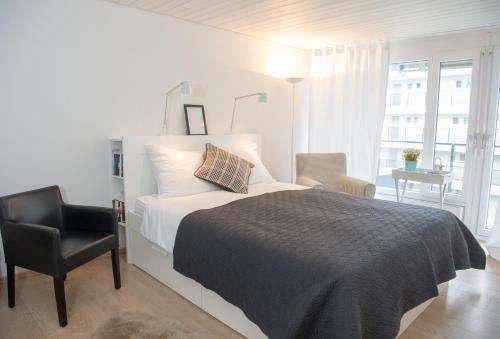 a bedroom with a bed and a chair and a window at Stylish apartment with mountain view in Lenzerheide