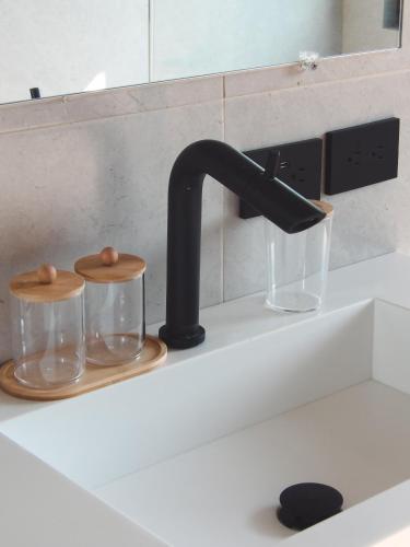 a kitchen sink with a black faucet and two glasses at Casa Matt & Marshall in Brisas de Zicatela