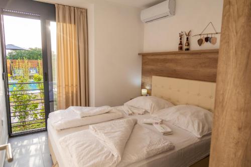 a bedroom with a white bed with a window at Kiteriders Garden Villas in Ulcinj