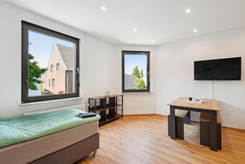 a room with a bed and a table and windows at Rheinische Gemütlichkeit, Sali Homes Zentrales Heim in Kleve in Kleve