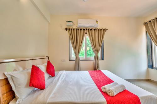 - une chambre avec un lit et des oreillers rouges dans l'établissement Golden Sun Ray's Villas, à Baga