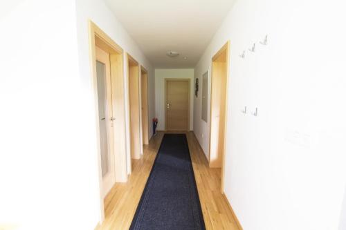 a hallway with white walls and a blue rug at Haus Johendre in Rennweg