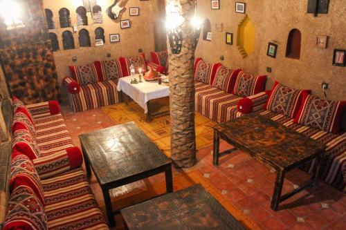 a living room with couches and a table and a tree at Riad Soleil du Monde in Zagora