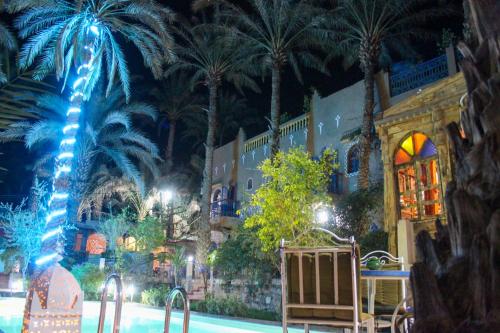 a resort with palm trees and a pool at night at Riad Soleil du Monde in Zagora