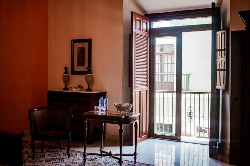 a room with a table and a balcony with a sliding glass door at Hotel Boutique Casa Don Gustavo, Campeche in Campeche