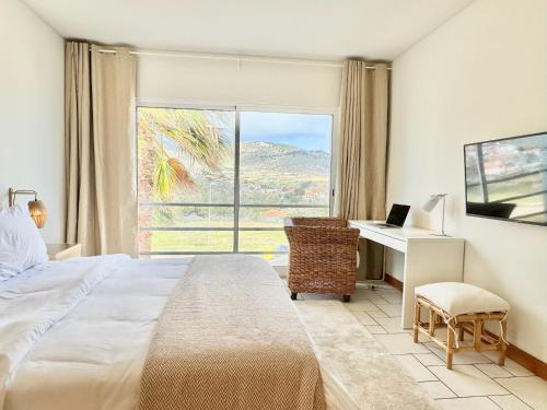 a bedroom with a bed and a desk and a window at Profetas GuestHouse in Porto Santo